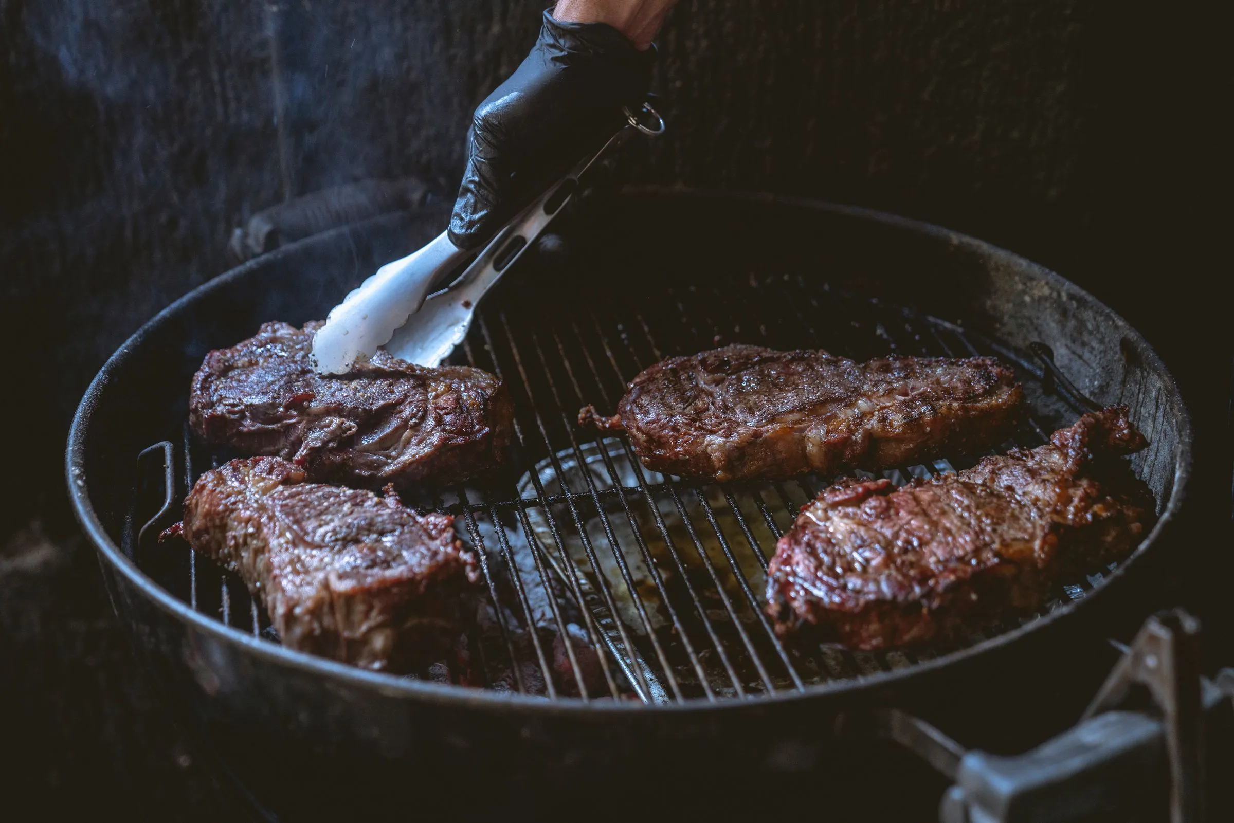 Piezas de carne a la brasa sobre parrilla redonda de carbón